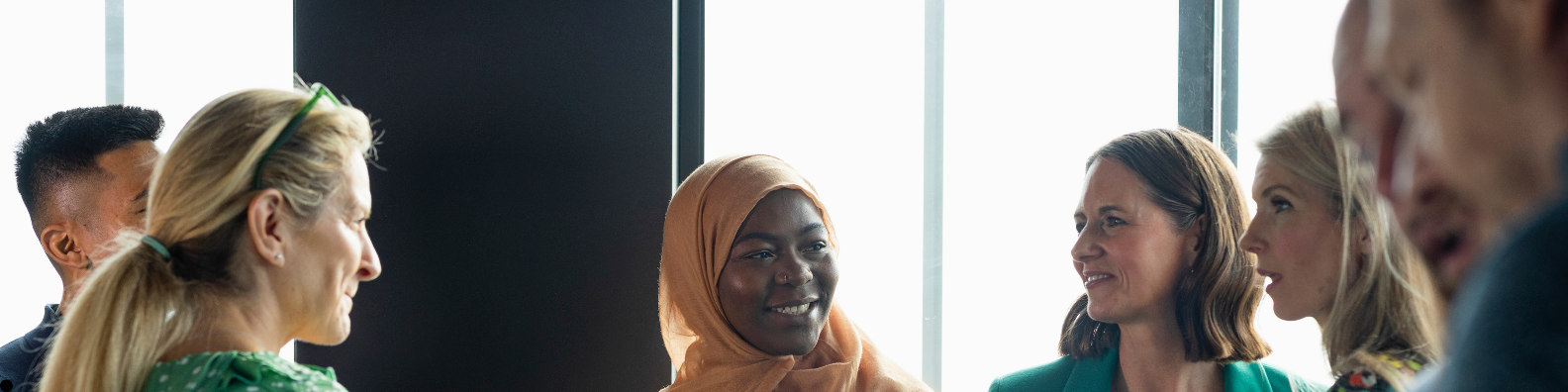 A group of community health & wellbeing workers (CHWWs) from diverse backgrounds smiling and talking together in a bright, welcoming space—illustrating the supportive, community-based approach of the CHWW programme in Westminster.
