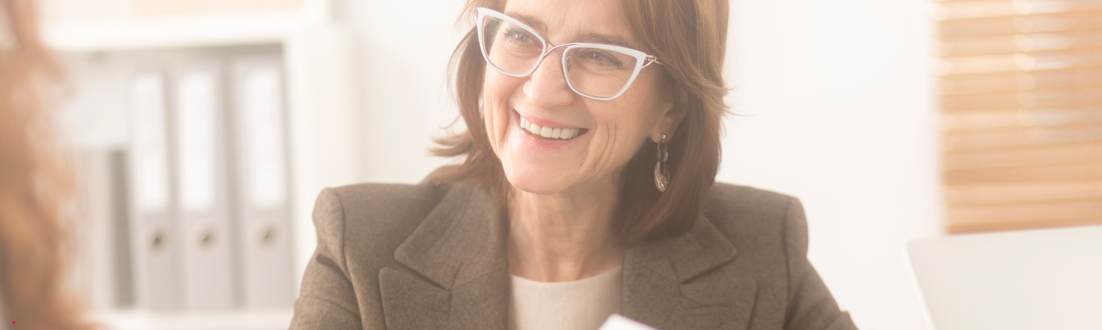 A Health & Wellbeing Coach smiles warmly during a one-on-one session, creating a supportive and welcoming environment for the person she’s working with.