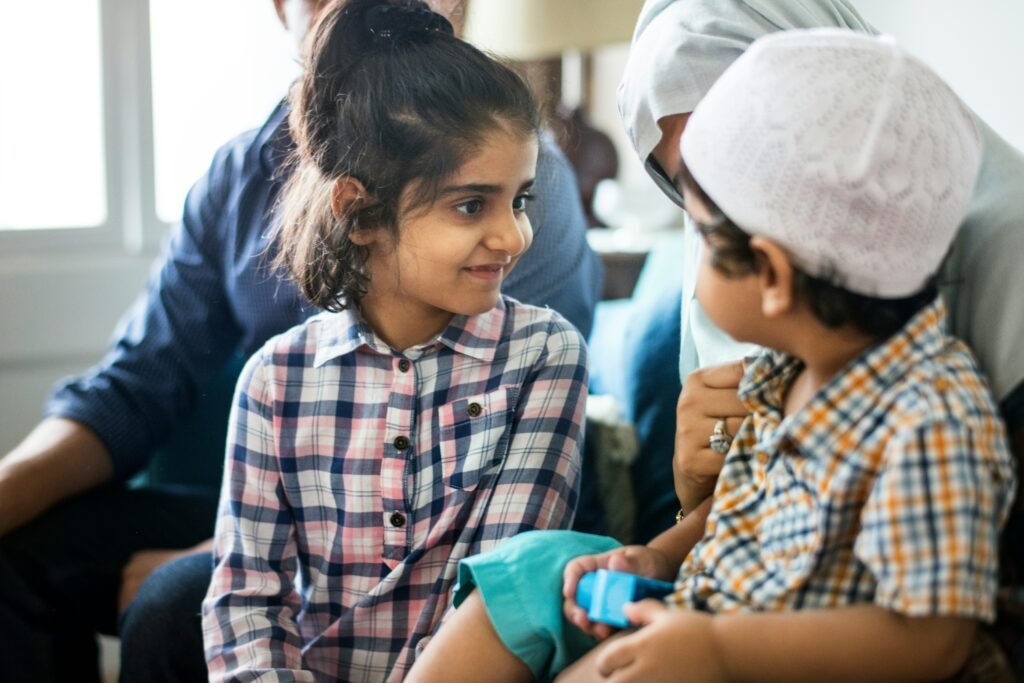 Boy looking at young girl sitting with woman